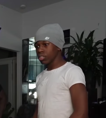 Rakai in a grey beanie and white T-shirt during a livestream, April 2025